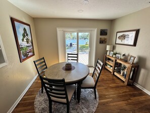 A dining area with a round table, four chairs, a small rug, and a wooden bench.