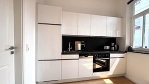 Una cucina moderna con mobili bianchi, un piano di lavoro nero e un forno integrato.