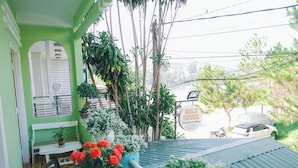 Fachada verde con un banco blanco, una mesa y plantas en macetas.
