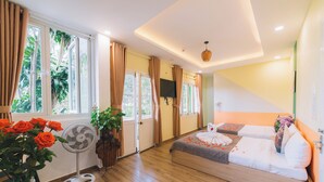 Un dormitorio con cama, ventilador, un florero con flores y ventana con cortinas.