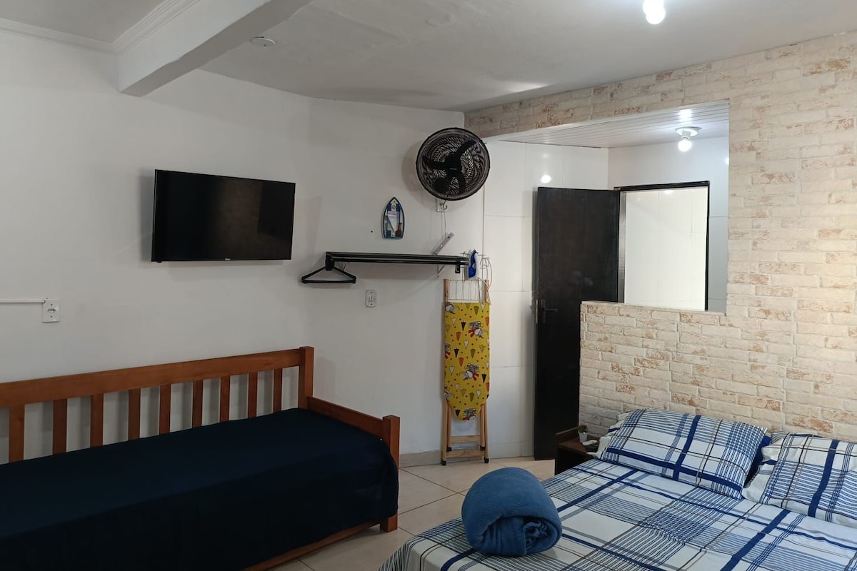A bedroom with a bed, a TV, a fan, and a mirror.