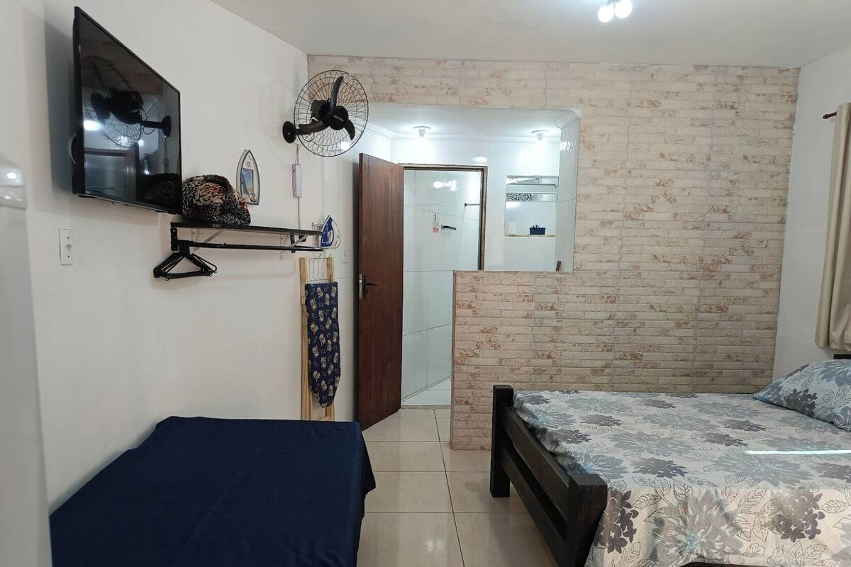 Un dormitorio con cama, televisor, ventilador y armario.