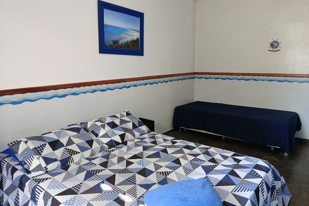 A room with a bed, a bench, a framed picture on the wall, and a decorative border.