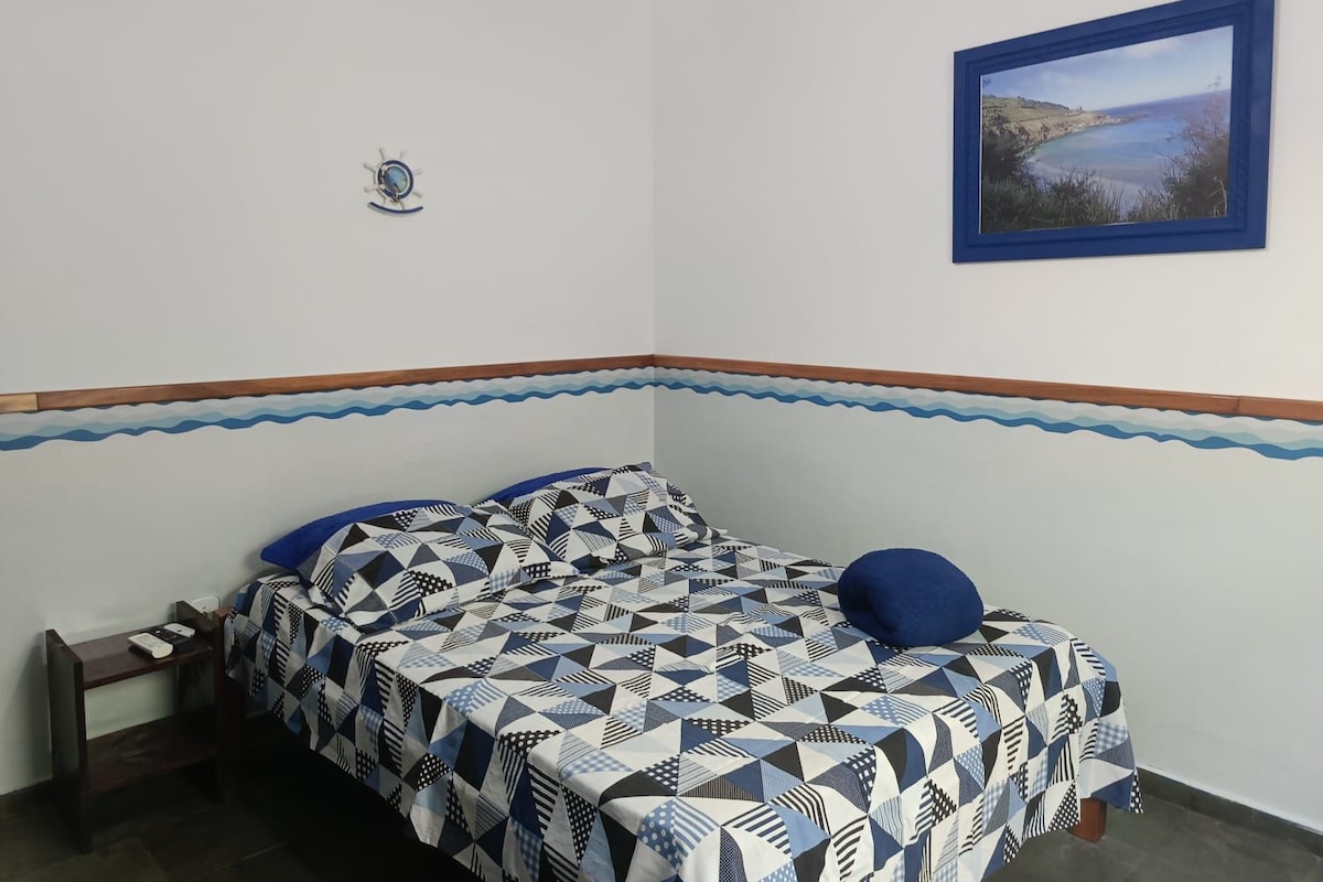 A bedroom with a bed, a nightstand, a wall clock, and a framed picture.