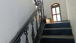 A staircase with ornate black railings leading to a landing. - Suítes e Kits da Natasha (Arraial do Cabo)