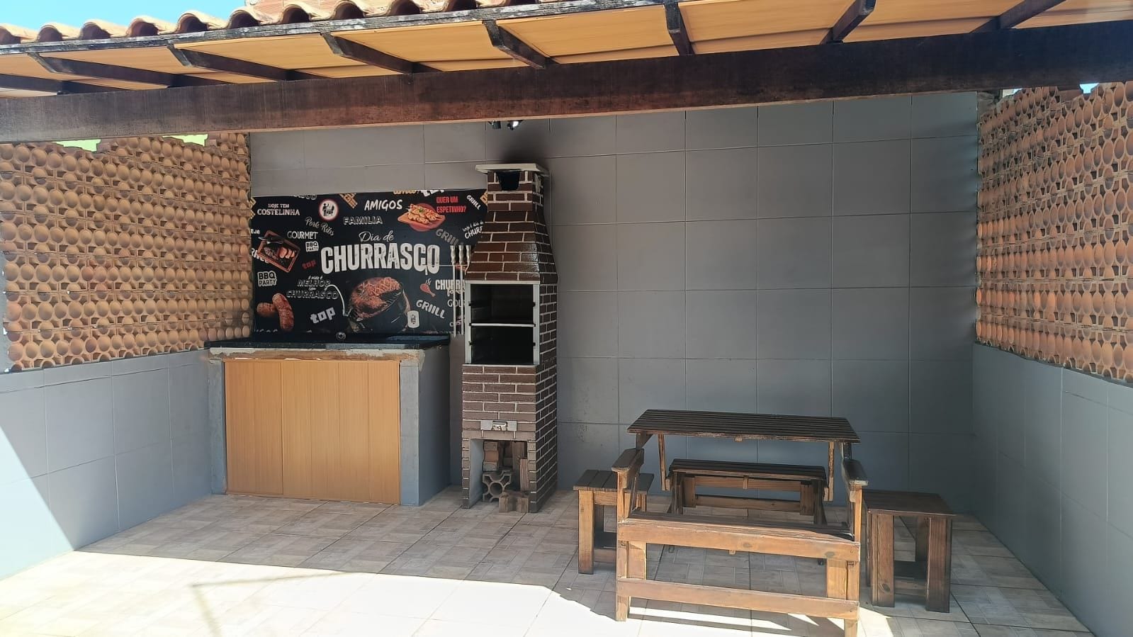 A patio area with a brick wall, a grill station, and a wooden bench.