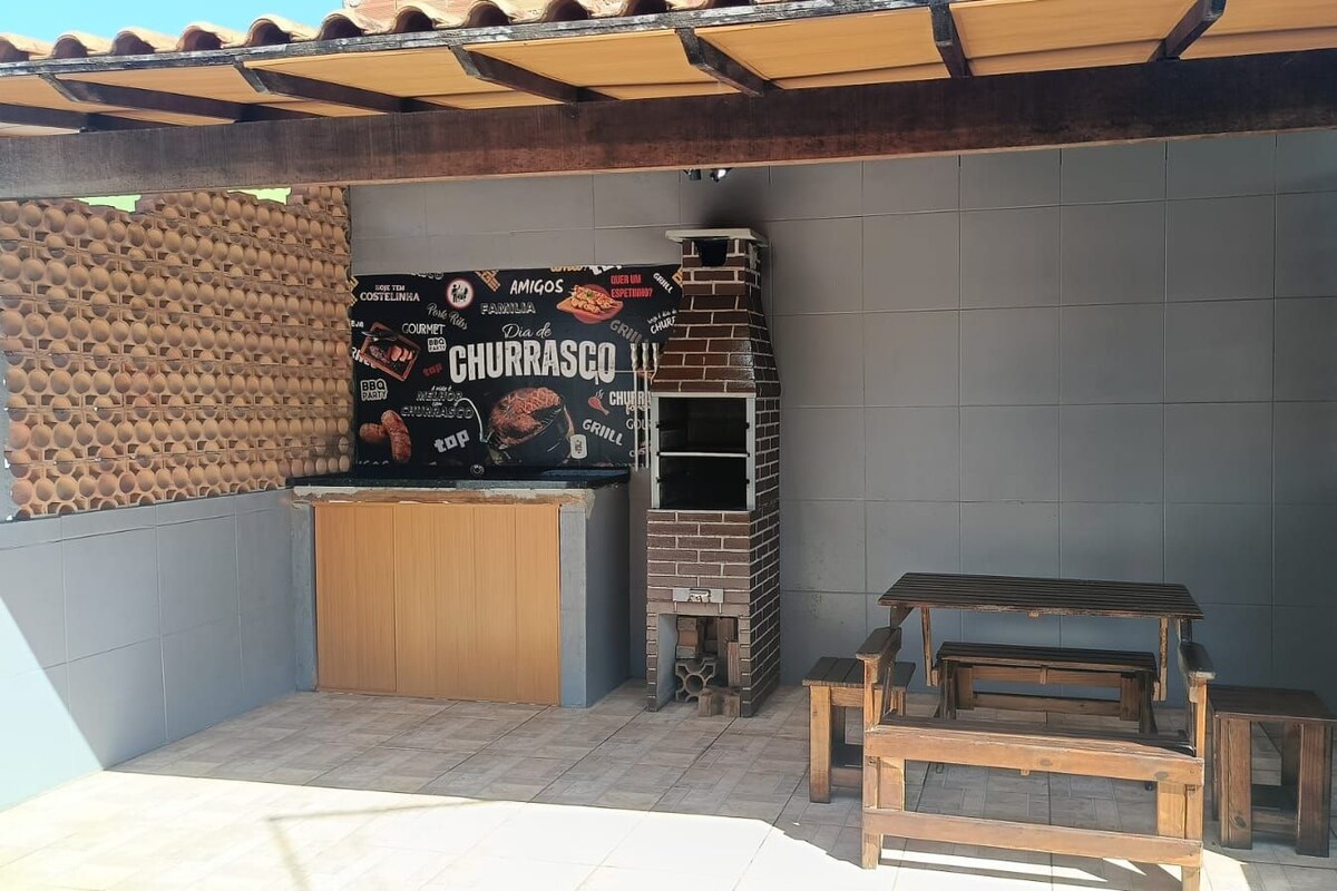 A patio area with a brick wall, a grill station, and a wooden bench.