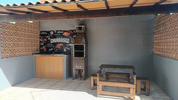 A patio area with a brick wall, a grill station, and a wooden bench.