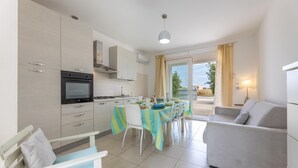A modern kitchen with a dining area, a sofa, and a view of the outdoors. - Villetta Soave - Santo Isidoro (Santo isidoro)