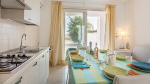 A modern kitchen with a dining area, a stove, and a view of the outdoors. - Villetta Soave - Santo Isidoro (Santo isidoro)