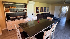 A dining area with a large table and chairs, a kitchen with a white door, and a living area with a couch and a ceiling fan. - Charming 3-bedroom barn with AC, WiFi in delightful Lava Hot Springs (Lava Hot Springs)