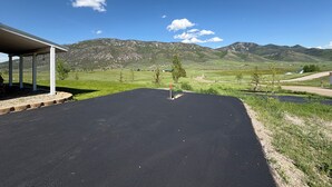 A covered outdoor area with a black surface, surrounded by green fields and mountains. - Charming 3-bedroom barn with AC, WiFi in delightful Lava Hot Springs (Lava Hot Springs)