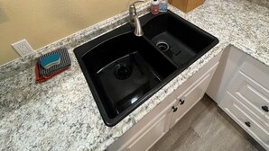 A kitchen with a double sink, granite countertop, and a framed picture of a cityscape on the wall. - Charming 3-bedroom barn with AC, WiFi in delightful Lava Hot Springs (Lava Hot Springs)