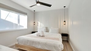 Een moderne hotelkamer met een groot bed, een plafondventilator en twee nachtkastjes.