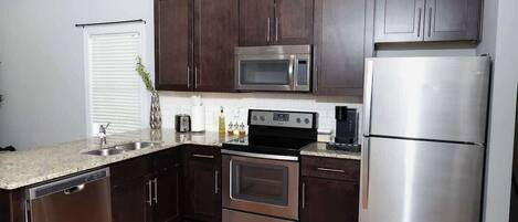 A modern kitchen with dark wooden cabinets, stainless steel appliances, and a granite countertop.