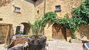 A stone building with arched doorways and a large potted plant in the foreground. - Arco-Navarra Rural House (Artariáin)