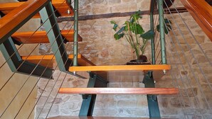 A wooden staircase with metal railings and a stone wall in the background. - Arco-Navarra Rural House (Artariáin)