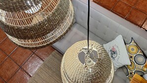 A dining area with a round table and chairs, surrounded by a stone wall. There are hanging woven light fixtures above the table. - Arco-Navarra Rural House (Artariáin)