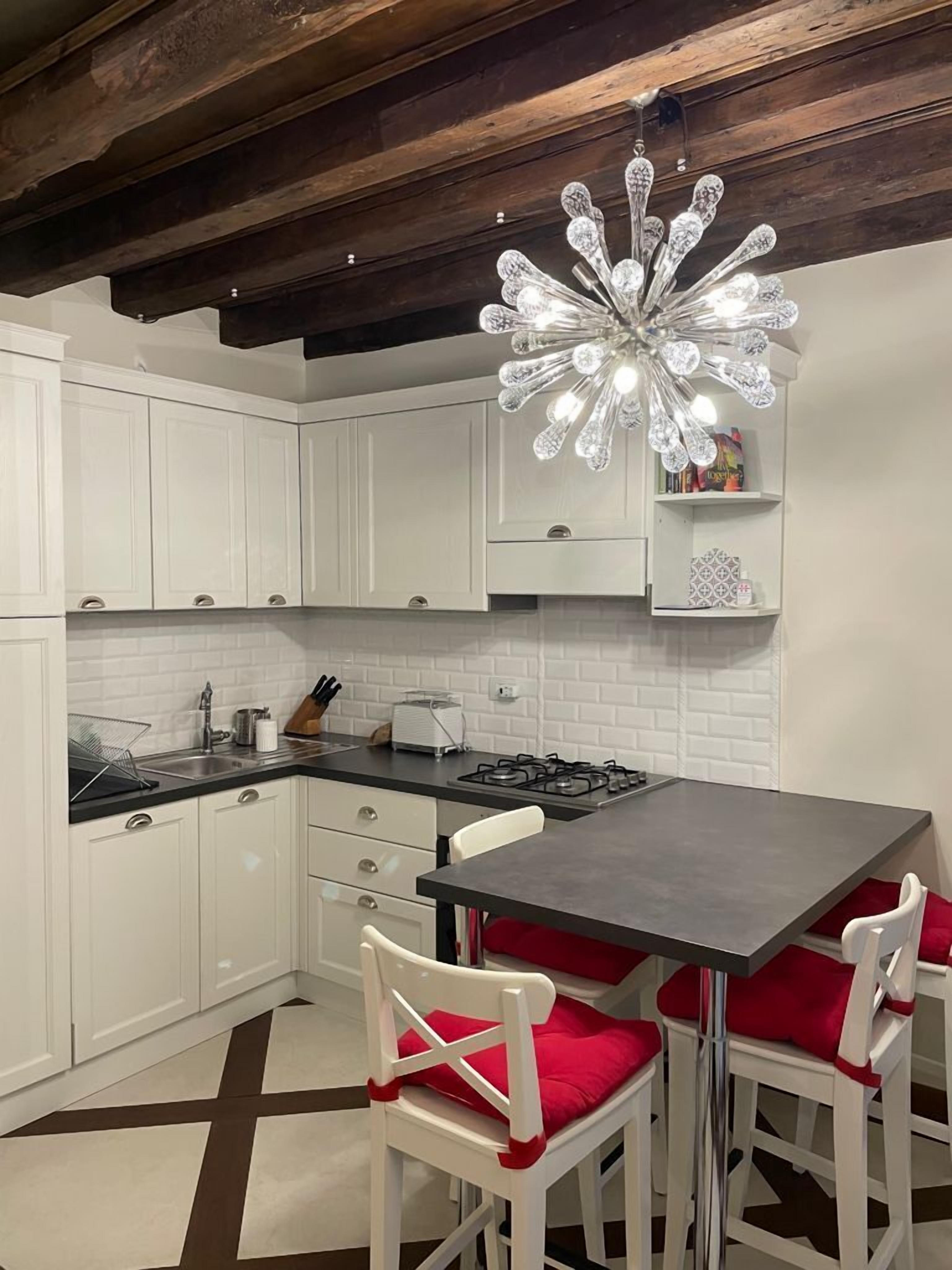 A kitchen with white cabinets, a dark countertop, a gas stove, and a chandelier.