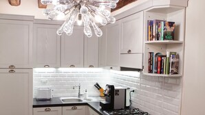 Una cocina moderna con armarios blancos, encimera negra y una lámpara de techo original.