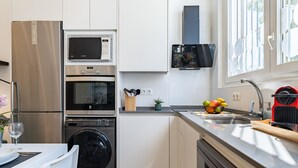 Een moderne keuken met roestvrijstalen apparatuur, een inbouwoven, magnetron en vaatwasser.