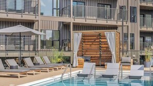 A rooftop pool area with lounge chairs, a wooden deck, and a view of the building's exterior.