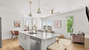 A modern kitchen with a central island, white cabinetry, and pendant lighting.
