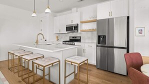 A modern kitchen with white cabinets, stainless steel appliances, and gold accents.