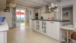 Een moderne keuken met een centraal eiland, witte kasten en uitzicht door de glazen deur.