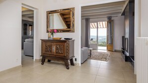 Een ruime zithoek met een houten kast, een grote spiegel en uitzicht op een balkon.