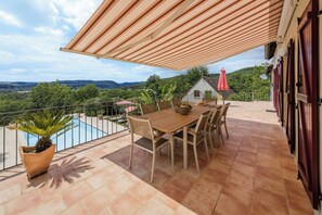A terrace with a pool, wooden table and chairs, and a view of the countryside. - Villa le Pechoir (Unknown)