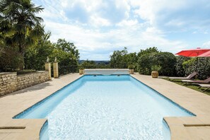 A rectangular swimming pool with clear blue water, surrounded by a stone wall and a paved deck. - Villa le Pechoir (Unknown)
