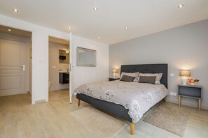 A bedroom with a bed, bedside tables, a mirror, and a bathroom visible through an open door. - Villa le Pechoir (Unknown)