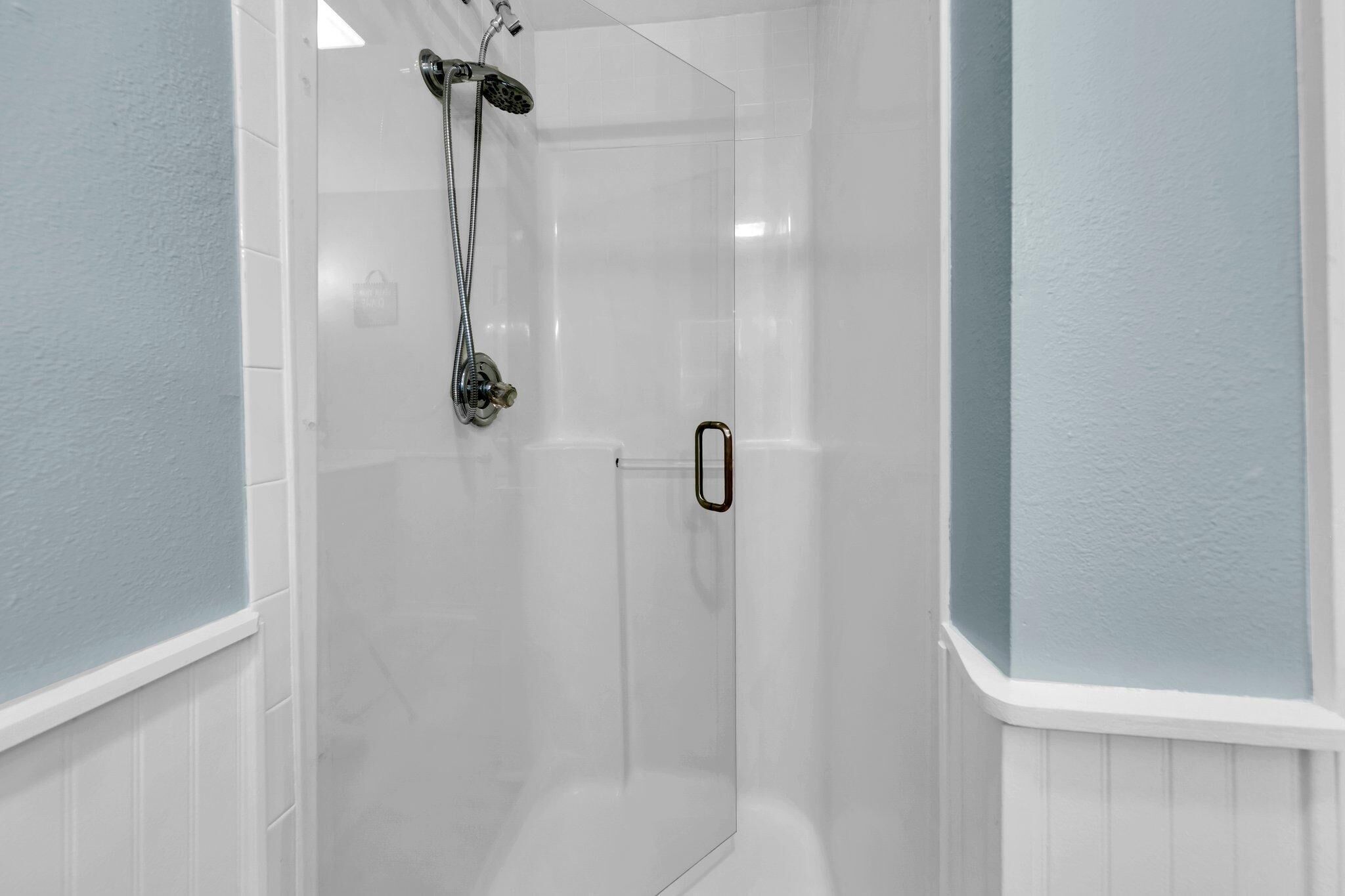 A modern shower with a glass door and a handheld showerhead.