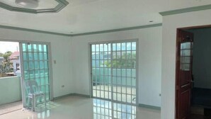 A room with a large window, a door, and a tiled floor. - Casa Solana (calmar, lucena city)