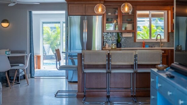 A modern kitchen with a large island, bar stools, and pendant lighting. - Sarasota Pool Home| Hot-tub| 2-miles to Siesta (Sarasota)