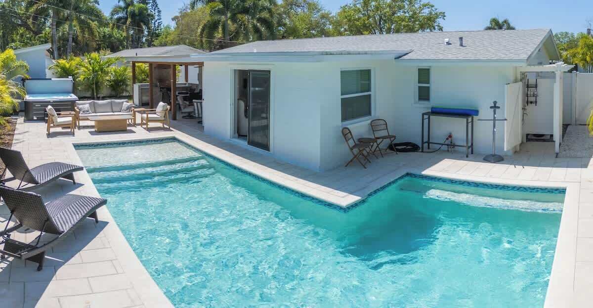 Une piscine avec une petite construction abritant un espace de repos extérieur et un coin barbecue à proximité.