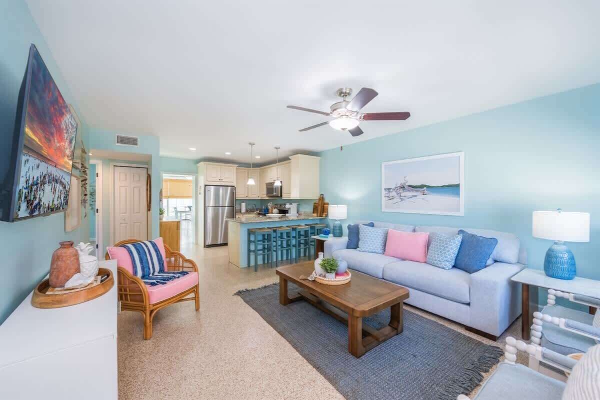 A spacious living room with a sofa, coffee table, and a dining area with a kitchen in the background.