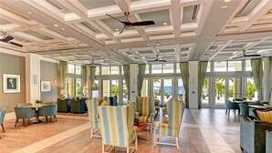 Un hall d’entrée spacieux, doté d’un haut plafond, de grandes fenêtres et d’un espace détente avec des chaises et des tables.