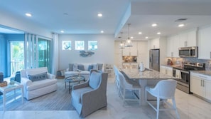 A modern kitchen with white cabinets, stainless steel appliances, and a marble countertop.