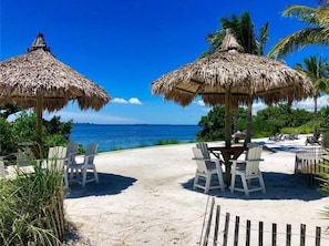 A beachside setting with thatched umbrellas, white chairs, and a view of the ocean.