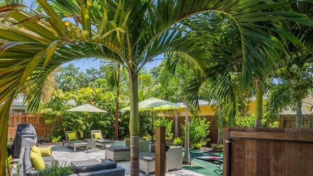 Un patio con mobiliario exterior, una parrilla y un cerco de madera.