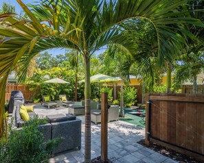 A patio area with outdoor furniture, a grill, and a wooden fence. - Downtown Living, Steps to Parks, Newly Furnished (Sarasota)