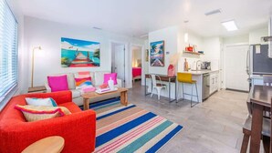 Un salón moderno con un sofá rojo, un tapete a rayas y un cuadro de una playa.