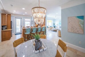 A spacious kitchen with wooden cabinets, a dining area with a marble table, and a large chandelier.