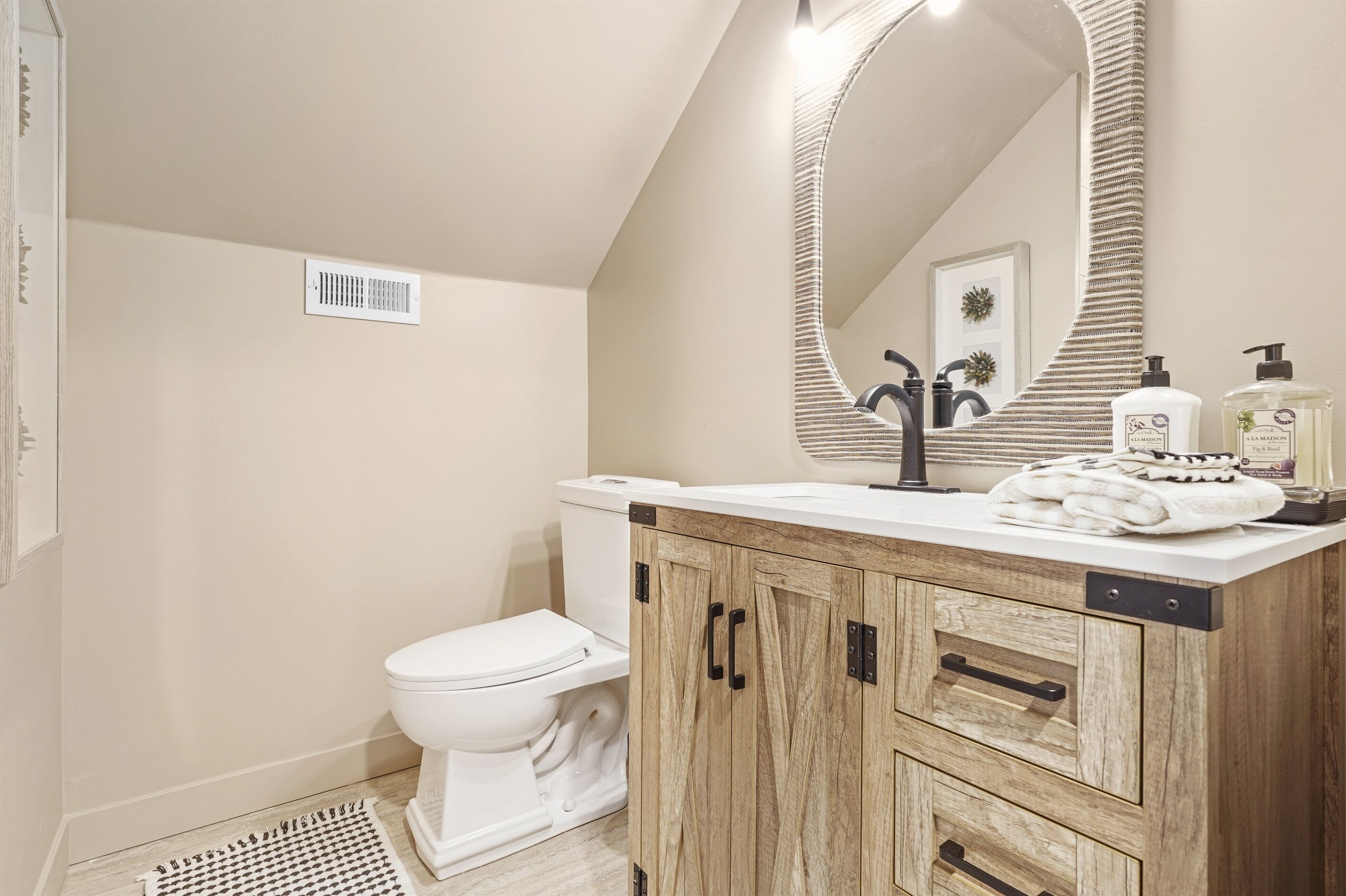 Une salle de bain moderne avec des toilettes blanches, un meuble-lavabo en bois et un grand miroir.