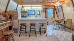 A cozy kitchen with a central island, bar stools, and a dining table with chairs. - A-Frame Cabin nestled in the trees - laundry, pet-friendly, close to village (Silver Star Mountain)