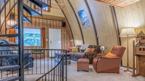 A cozy, wooden interior with a curved ceiling, a staircase, a sofa set, and a globe on a side table. - A-Frame Cabin nestled in the trees - laundry, pet-friendly, close to village (Silver Star Mountain)
