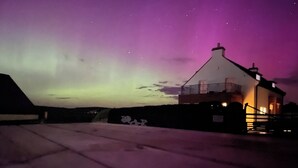 A building with a sloped roof and a balcony, surrounded by snow. - 3 bedroom house (Bushmills)