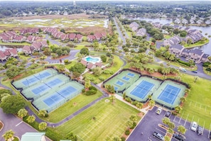 A residential area with multiple tennis courts, a swimming pool, and a large parking lot.